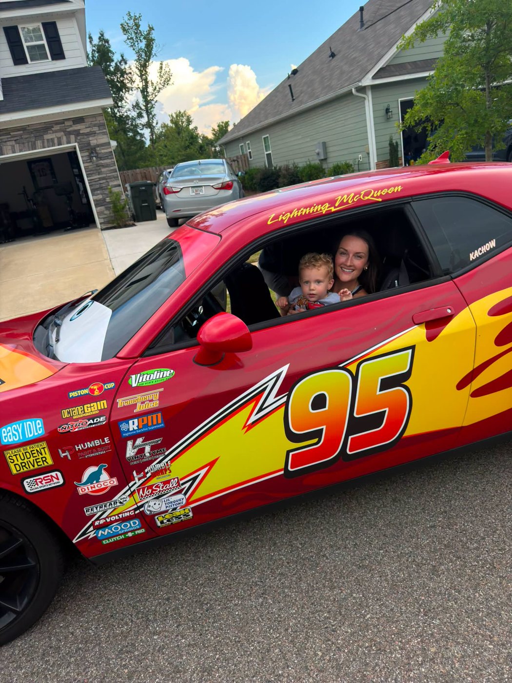 A mom and her toddler smiling from the driver's seat of the McQueen Augusta car